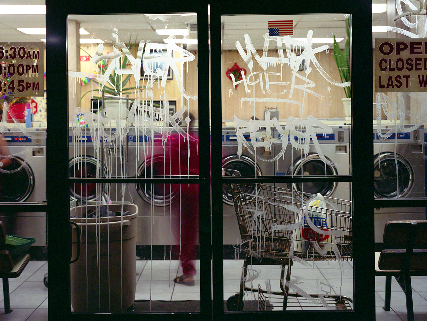 Image of glass doors to a laundromat with grafiti covering the glass
